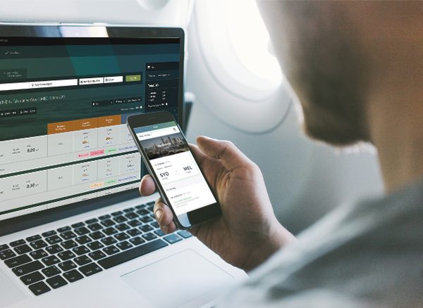 Man using Lightning online booking tool on laptop and mobile while in flight